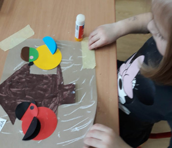 dziecko podnosi wykonaną pracę z drzewem w tle