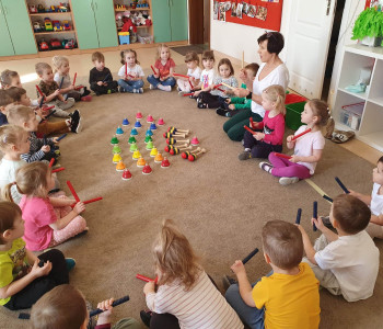 dzieci siedzą na podłodze i trzymają instrument muzyczny