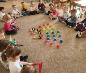 dzieci siedzą na podłodze i trzymają instrument muzyczny 2