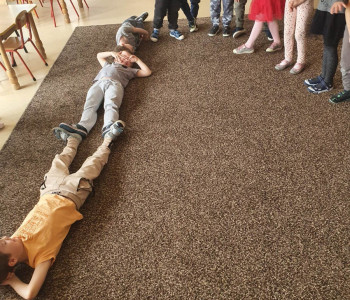 Dzieci leżą na podłodze - poznają sposoby mierzenia długości