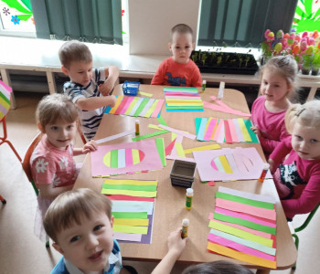 Dzieci wyklejają pisanki na papierze